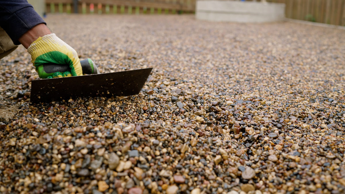 Web Stone Depot Landscaping Supplies South Lyon Michigan Gravel Installation A worker uses a trowel to smooth out decorative gravel